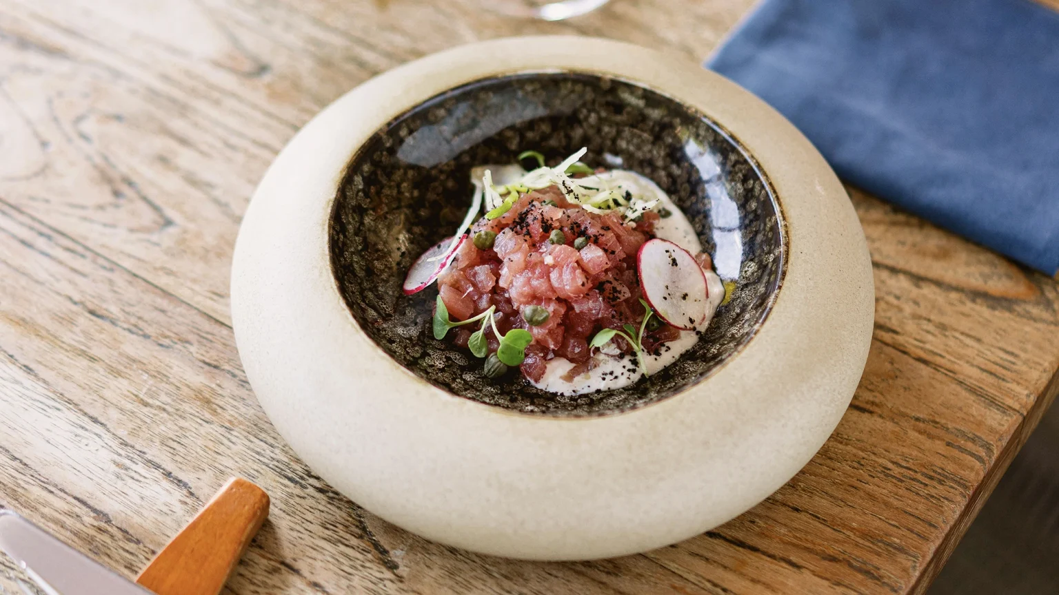 Raw tuna crudo served in a white bowl at this fish restaurant on Kleo rooftop