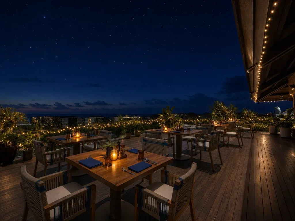 Open-air rooftop dining at Bonito, KLEO Seminyak, at night with candlelit tables and the city lights beyond.